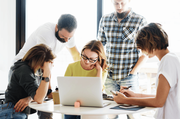 Group of market researchers around a laptop discussing recruiting user research participants for their user research